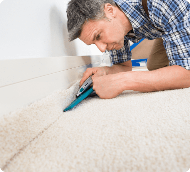 A man cutting the carpet with a pair of scissors.