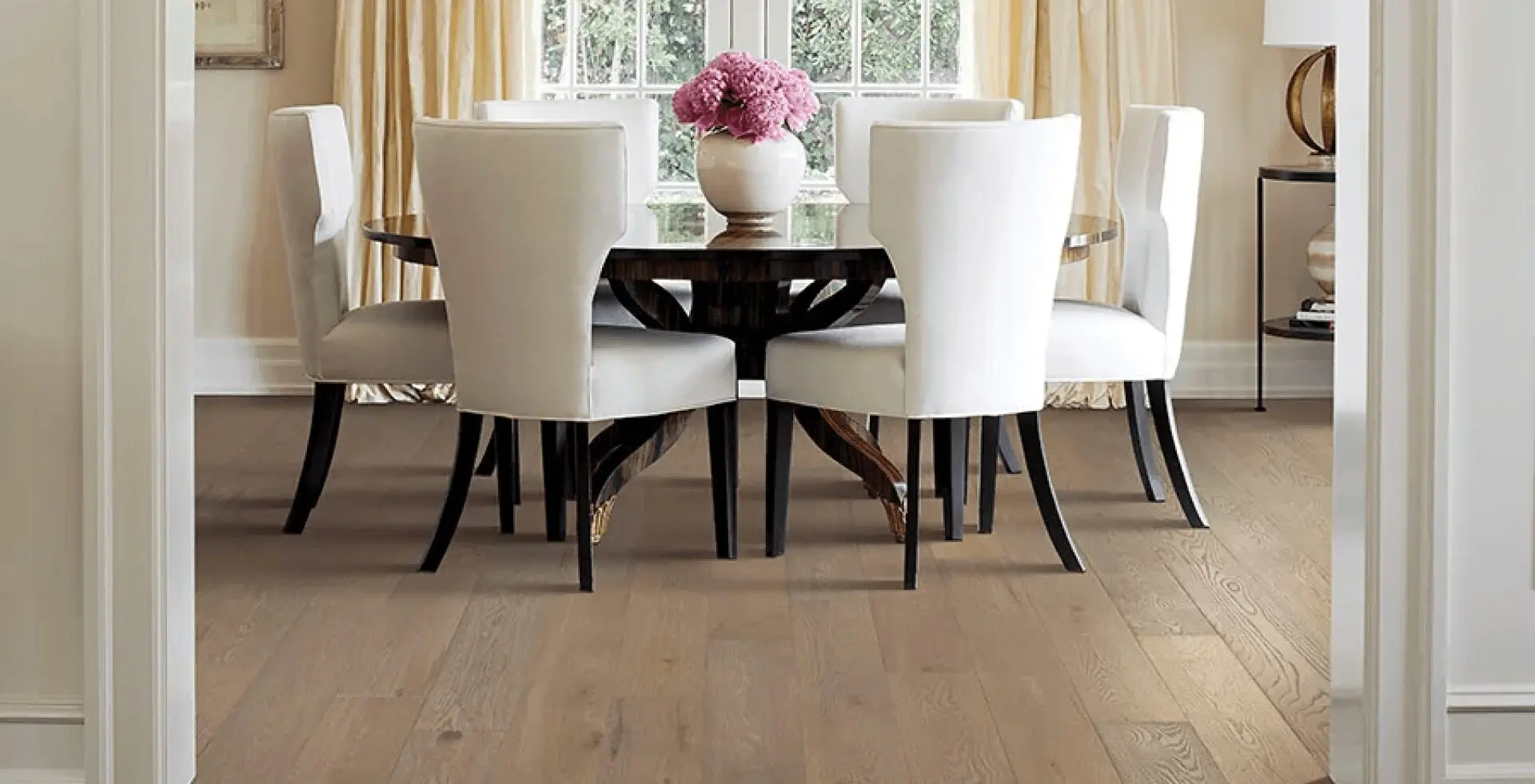 A dining room table with white chairs and a vase of flowers.